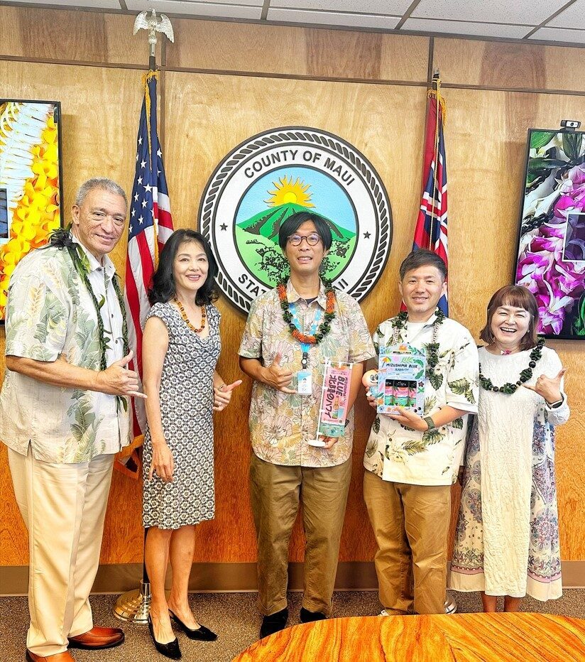 2025年5月27日（火）マウイ郡長へ山火事災害の寄付を持参写真左から、マウイ郡長：リチャード・T・ビッセン様、通訳：KYOKO KIMURA様、株式会社マップトラベル 代表取締役 大道哲平、同社 常務取締役 疋田 賢士 、ハワイ福井県人会 会長 深草 しのぶ 様